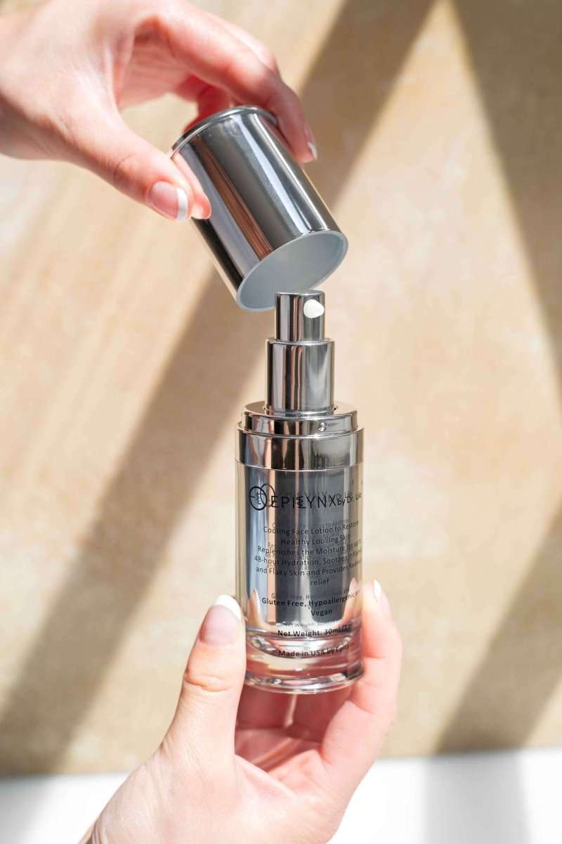 Hand holding a silver face moisturizer bottle with flip-top lid