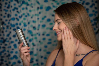 Face moisturizer bottle held near cheek for applying