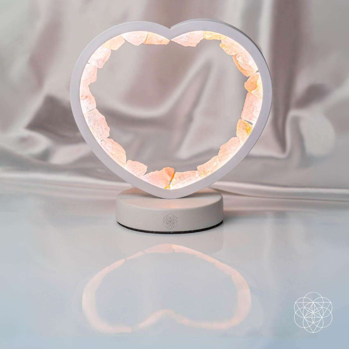 Rose quartz heart lamp with gray frame and glowing ring on a white base