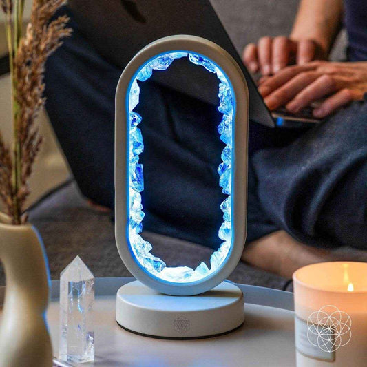Clear quartz achievement lamp with oval blue-lit frame and white base on table