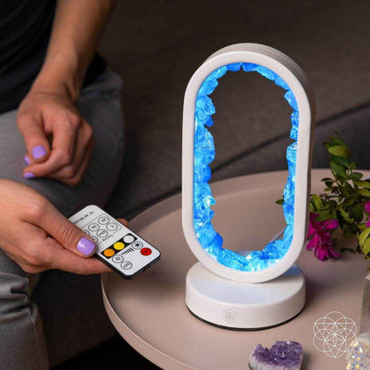 Clear quartz achievement lamp with oval frame, blue glowing interior, white base, remote