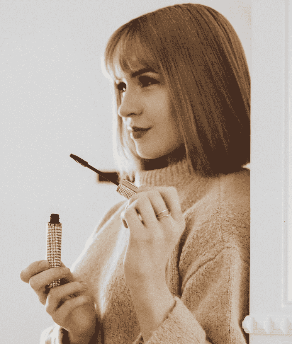 Rhinestone-embellished vegan mascara wand held near eyelashes in dark color