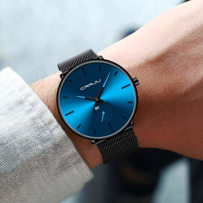 Blue minimalist wrist watch on wrist, black mesh band and blue dial with teal details
