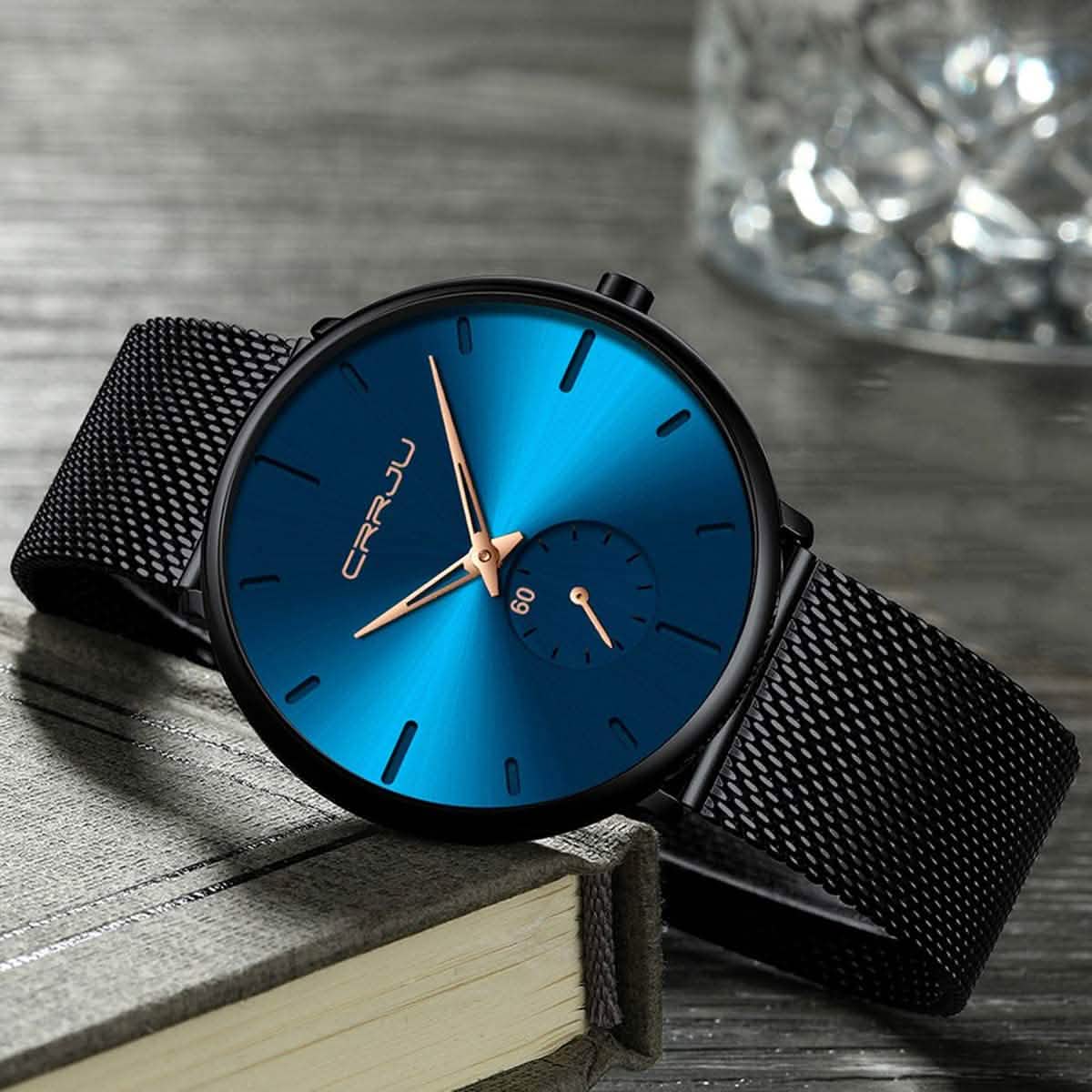 Blue minimalist wrist watch with black mesh band, blue dial and gold-toned accents