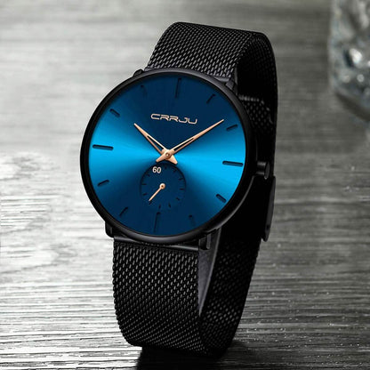 Blue minimalist wrist watch with black mesh band, blue face and gold-toned hour markers