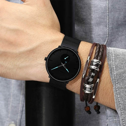 Men's minimalist waterproof wrist watch on wrist with black mesh strap and black dial, teal accents