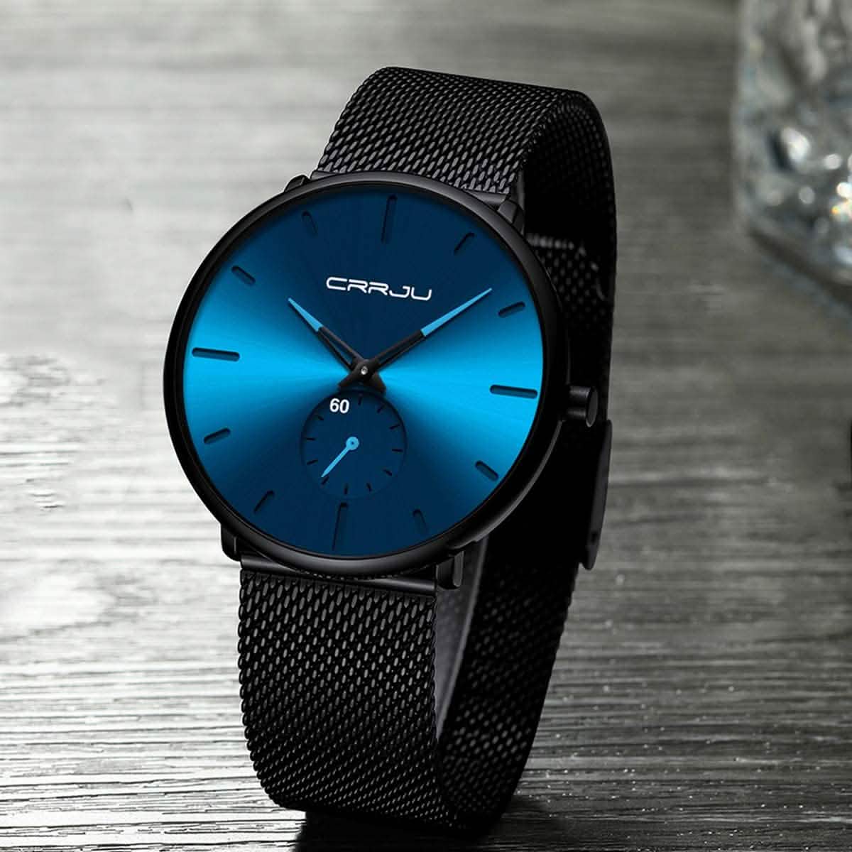 Blue minimalist wrist watch with black mesh band, blue dial and teal hour/minute hands