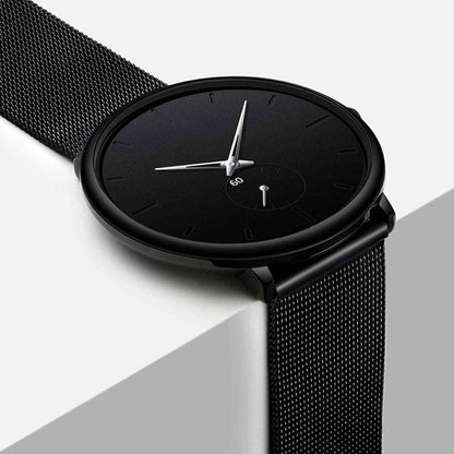 Black wrist watch with round case and black mesh strap, side angle