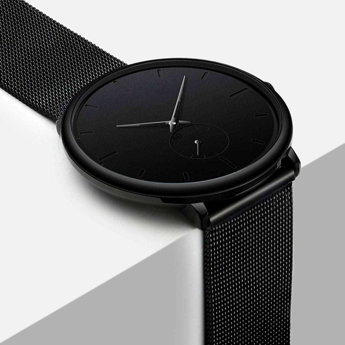 Men's minimalist waterproof wrist watch with black mesh strap and black face, side view