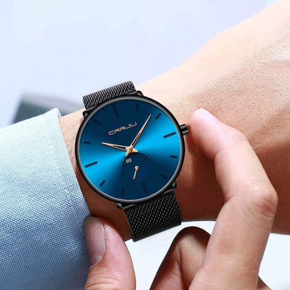 Blue minimalist wrist watch with round dial and black mesh strap on hand