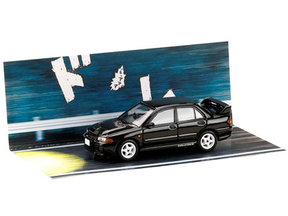 Black diecast Lancer Evolution III car on blue diorama street, wider angled view