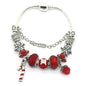 Red crystal Christmas charm bracelet with silver-tone links, nutcracker and bell charms