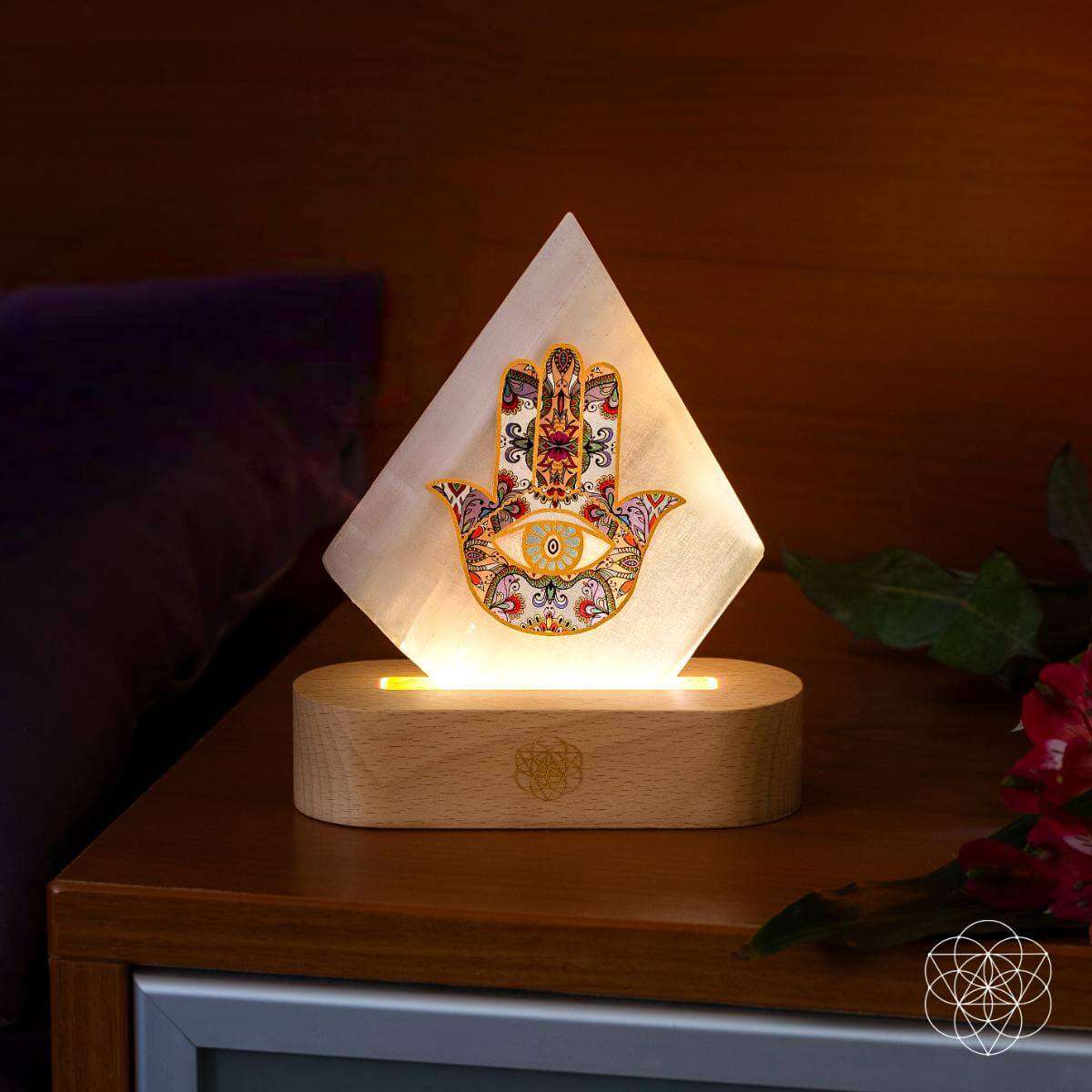 Hamsa-pattern triangular mood lamp on wooden base with warm glow