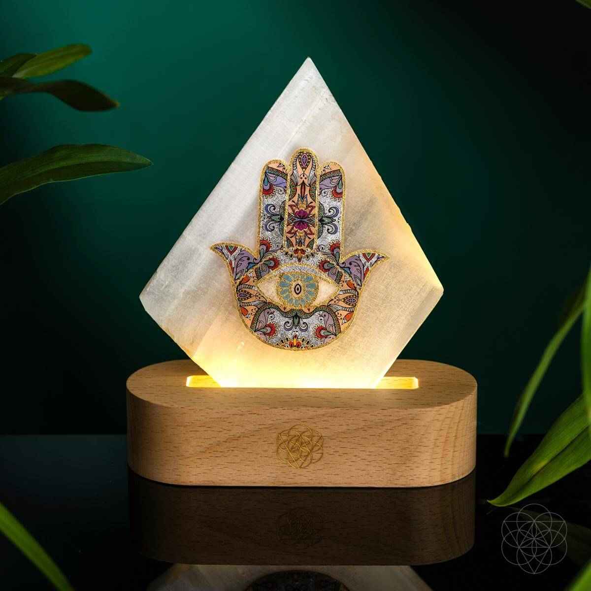 Hamsa-pattern triangular mood lamp on circular wooden base with warm light