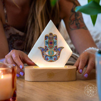 Hamsa-pattern triangular mood lamp on wooden base, held by hands