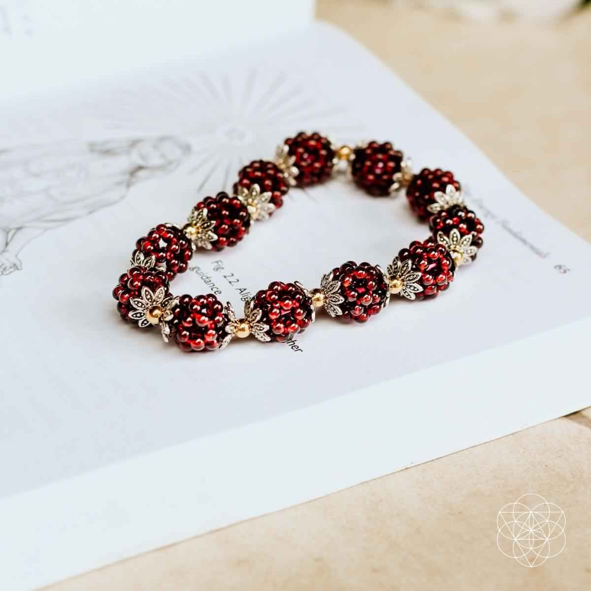 Natural garnet healing bracelet on display card, red beads and gold flower charms