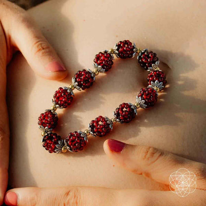 Natural garnet healing bracelet on palm, red beads with gold floral spacers