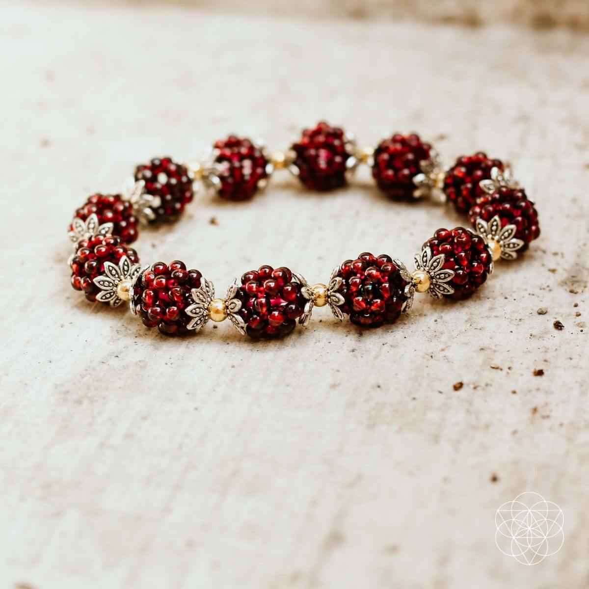 Natural garnet healing bracelet close-up, red bead cluster with gold metal details