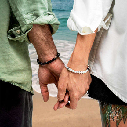 Two wrists wearing black and white beaded bracelets with silver-toned accents on both hands