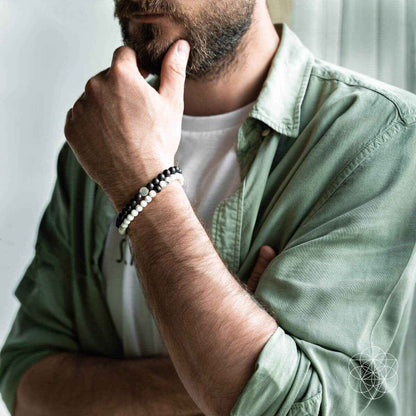 Black-and-white beaded bracelet set on a man’s wrist with silver-toned bead accents