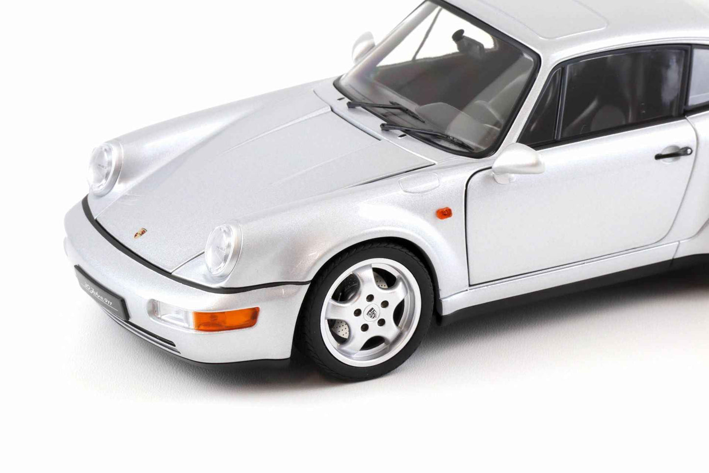 Silver Porsche 911 die-cast model car close-up, front bumper, headlights, and four-spoke wheel