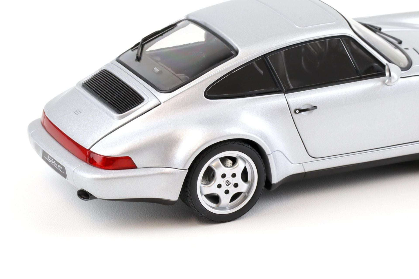 Silver Porsche 911 die-cast model car close-up, rear lights, grille, and four-spoke wheel