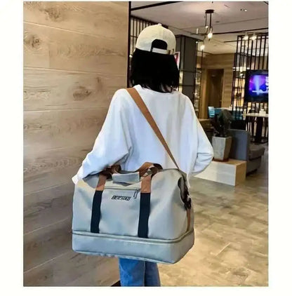 Light gray nylon duffel bag with brown straps and black side stripe