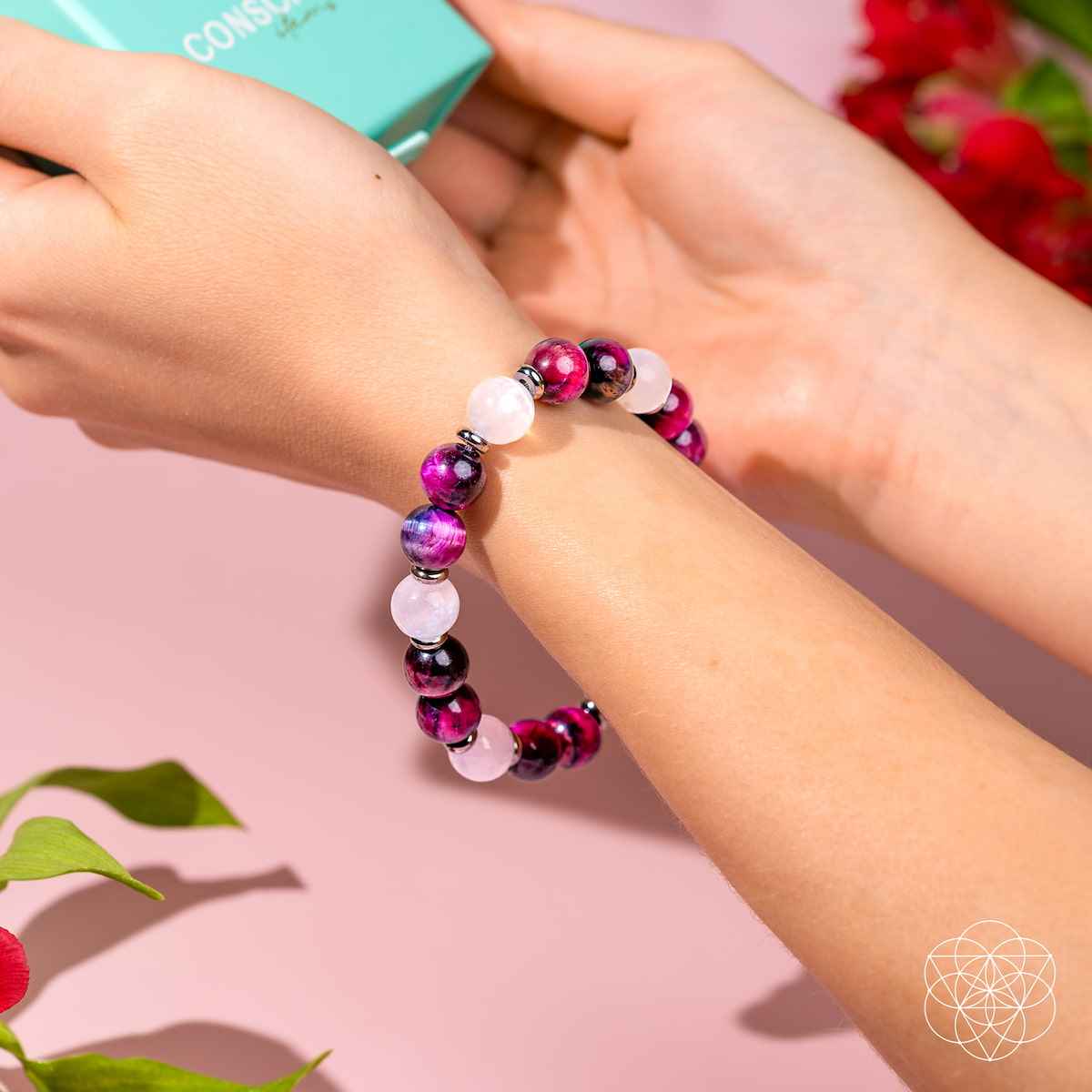 Beaded bracelet on wrist with magenta beads and white stone beads.