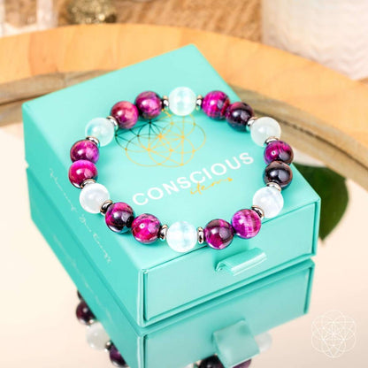 Bracelet resting on turquoise gift box with magenta beads and white stones.