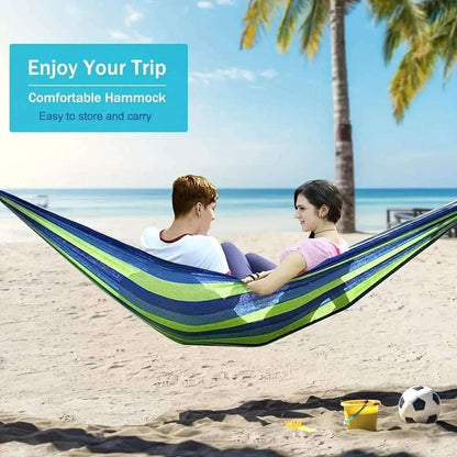Striped portable hammock with blue and green fabric, resting on a sandy beach