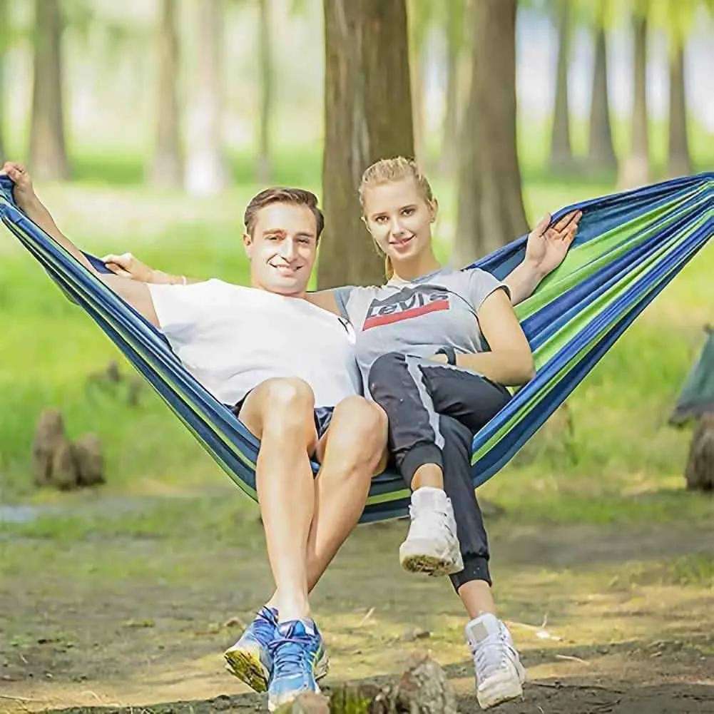 Striped portable hammock with blue and green fabric, shown in use between two ends
