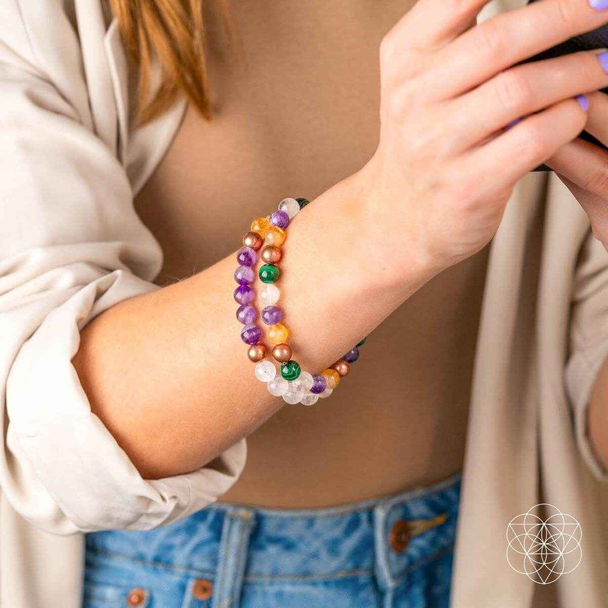 Triple beaded crystal bracelet set on wrist with purple, green, orange, and clear beads