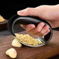 Garlic rocker press with black handle and stainless perforated grating plate