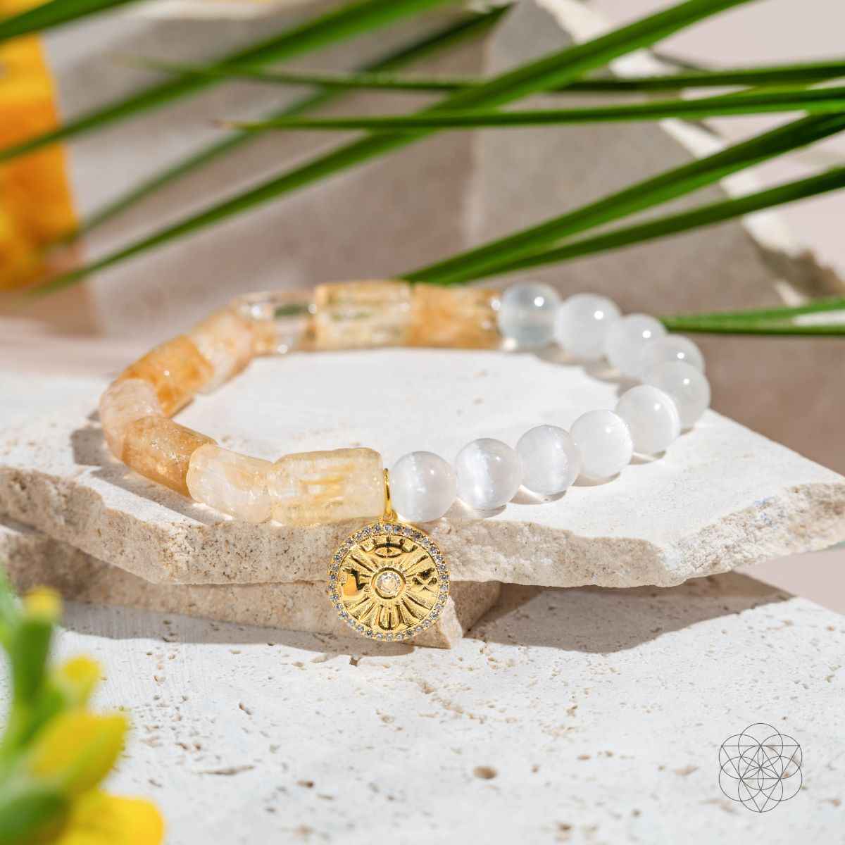 Citrine and selenite bracelet with gold sun medallion charm on stone surface