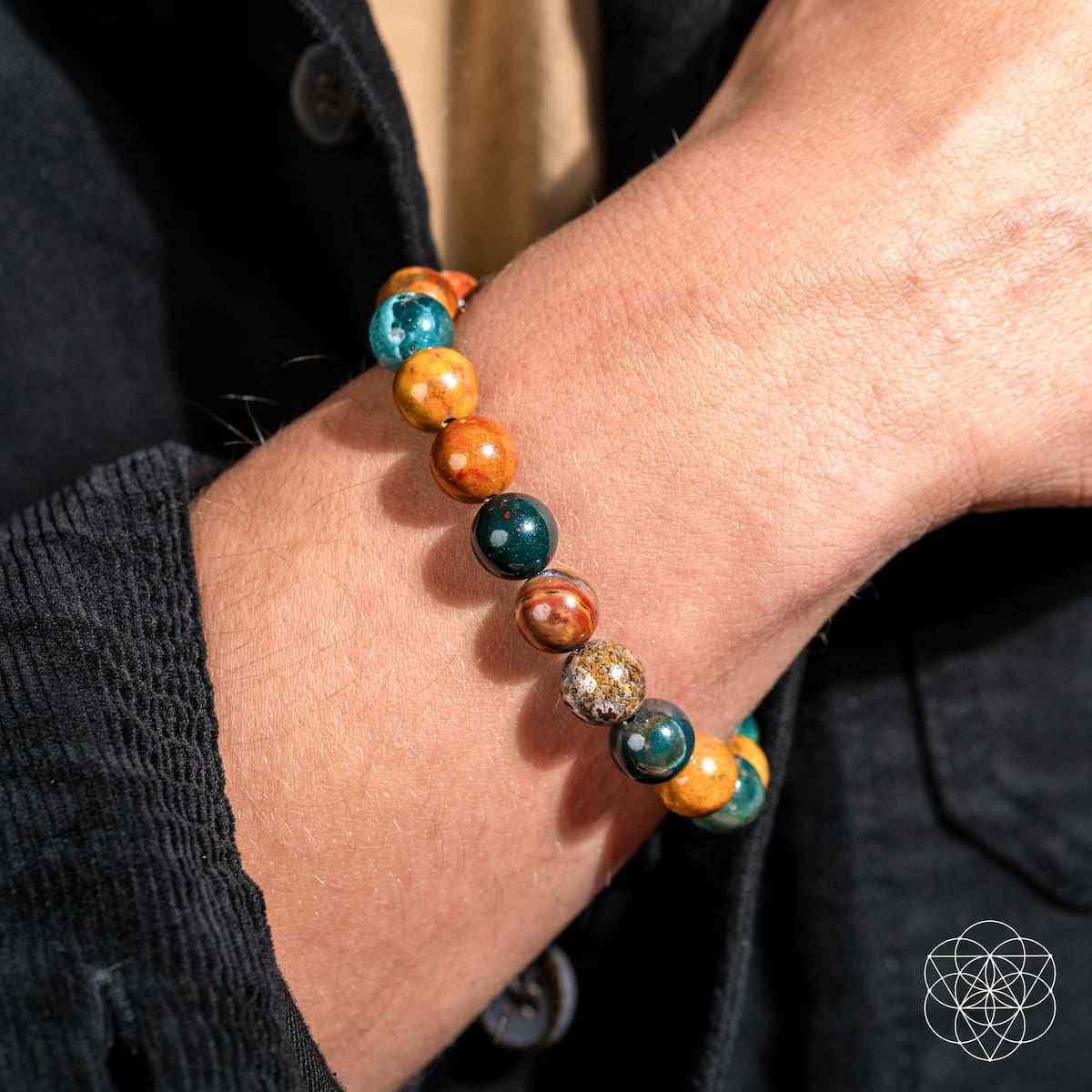 Beaded bracelet on wrist with teal, orange, and dark green speckled beads