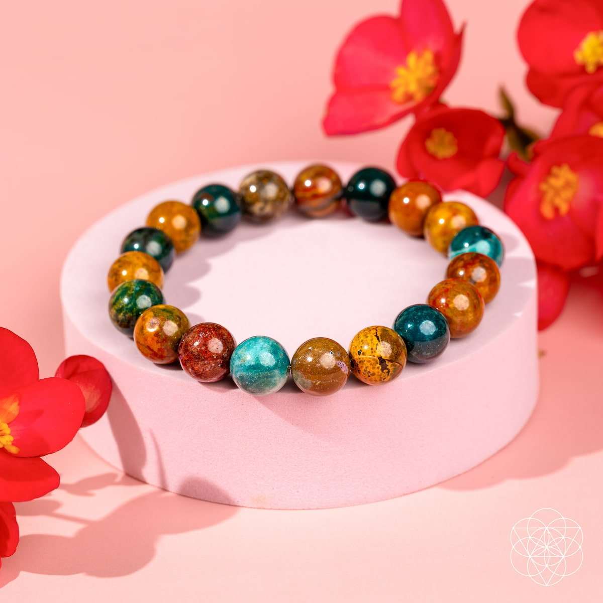 Beaded bracelet on a white stand with teal, orange, and dark green round beads