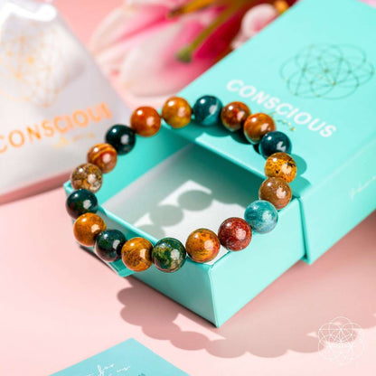 Beaded bracelet on teal gift box with teal, orange, and dark green round gemstone beads