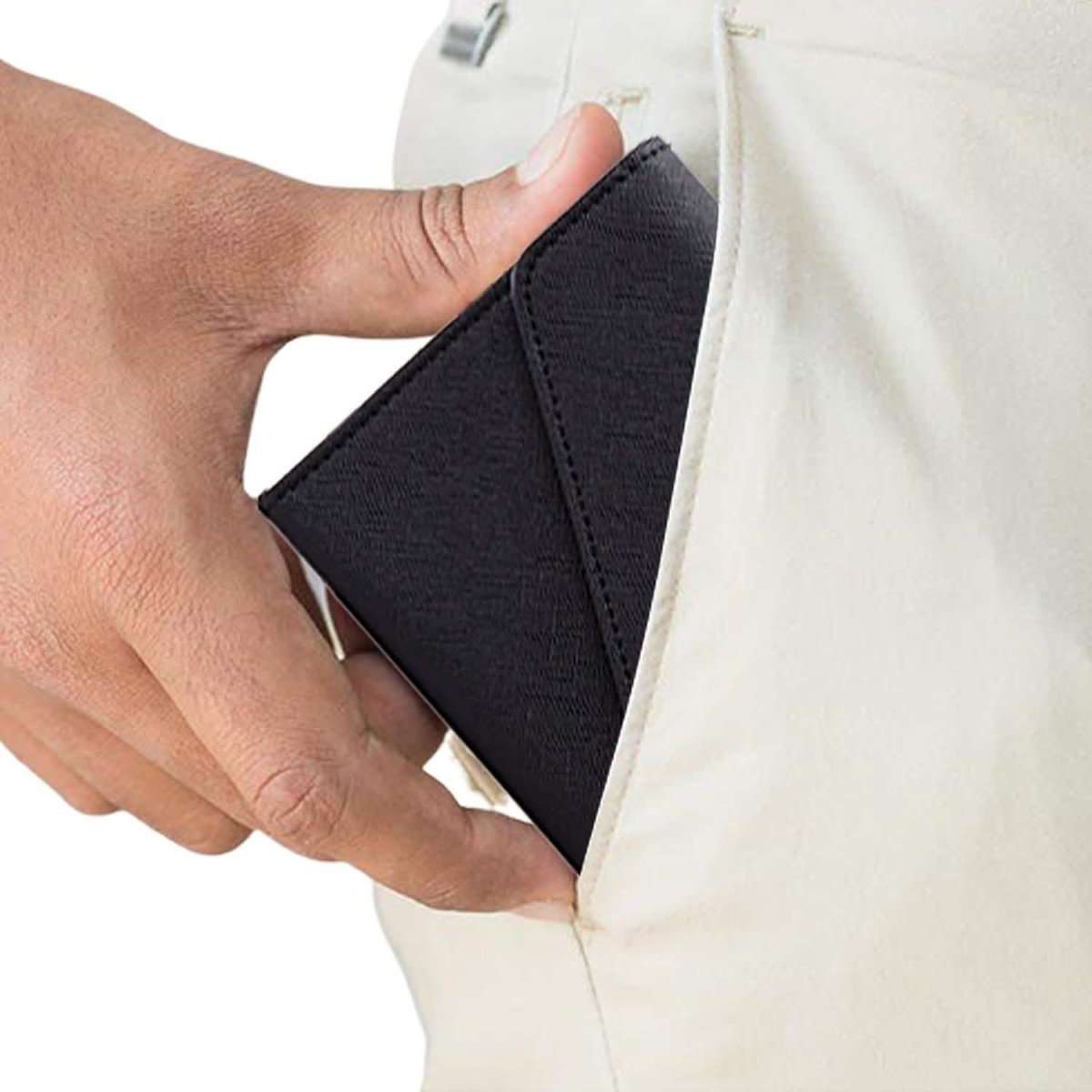 Black passport organizer wallet being placed into a jacket pocket, snap closure visible