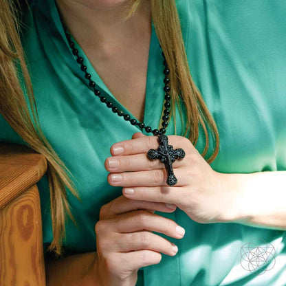 Black beaded cross pendant necklace with ornate crucifix held in hands
