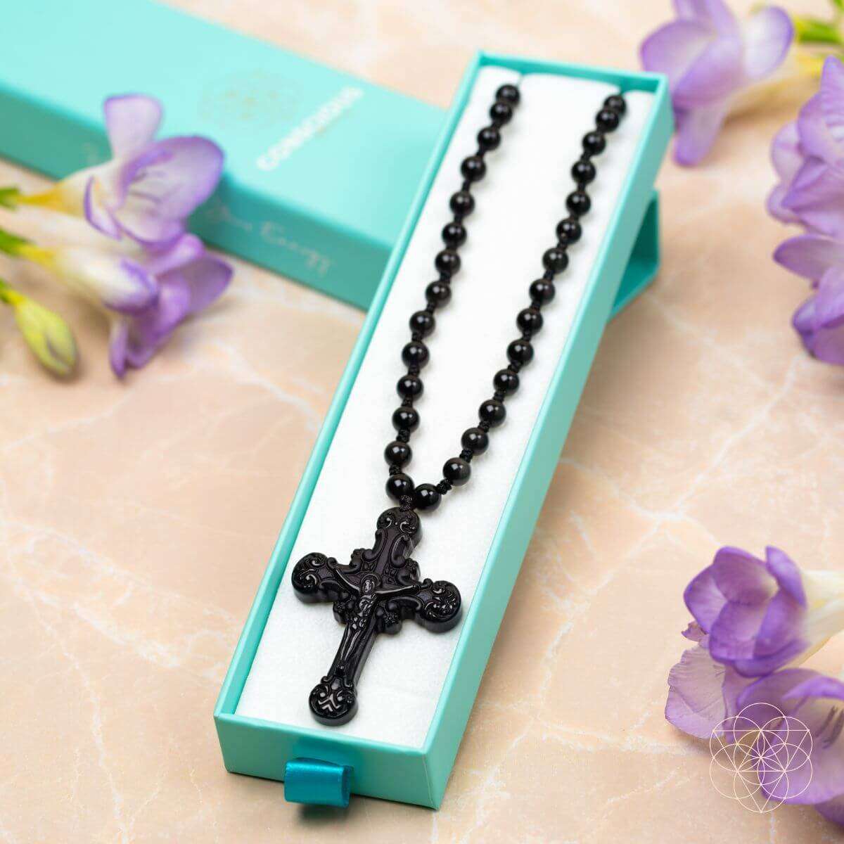 Black beaded cross pendant necklace shown in box with ornate crucifix pendant
