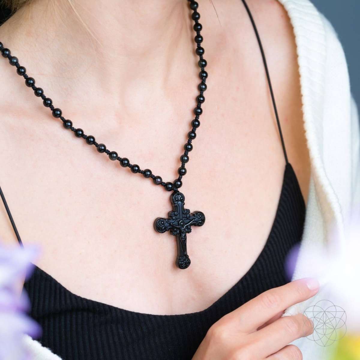Black beaded cross pendant necklace with ornate crucifix at collarbone