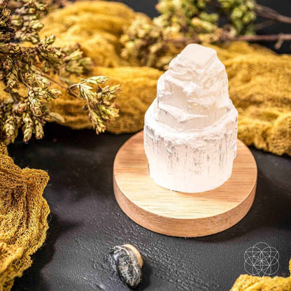 White selenite cleansing lamp crystal on round wooden base