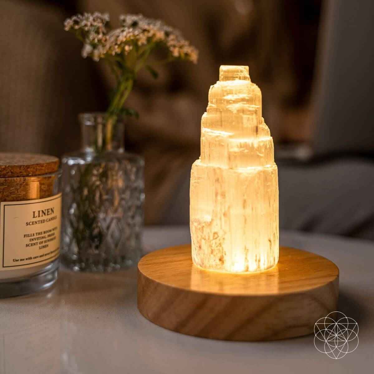 Selenite cleansing lamp with glowing amber crystal on round wooden base