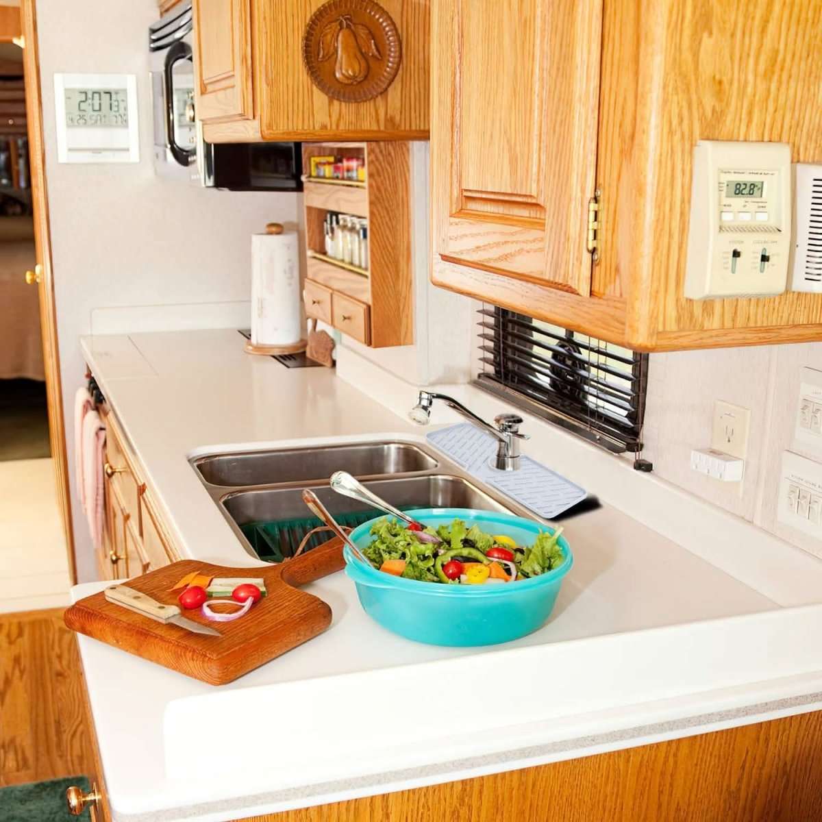 Light gray silicone kitchen sink mat with faucet cutout and ridged surface