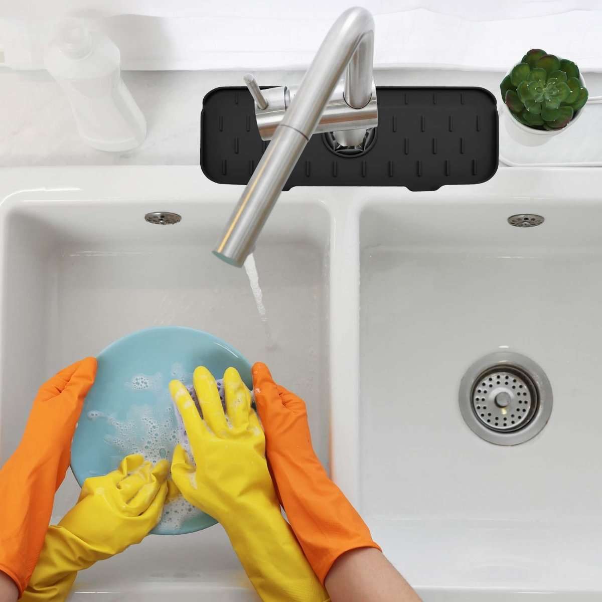 Black silicone sink mat splash guard with faucet during cleaning