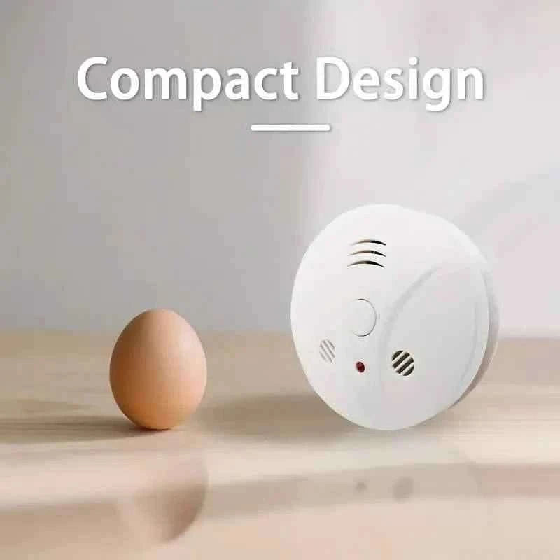 Compact smoke alarm, white round unit with speaker vents and red indicator light