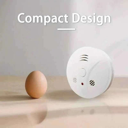 Compact smoke alarm, white round unit with speaker vents and red indicator light