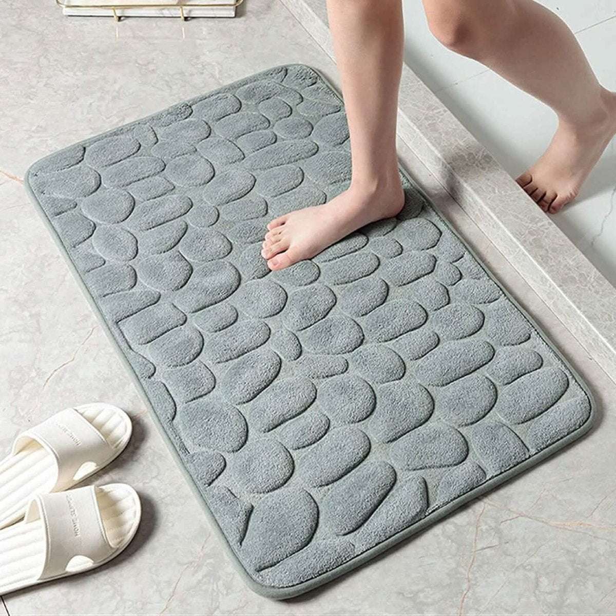 Gray-blue cobblestone embossed memory foam bath mat with non-slip backing.