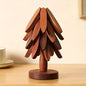 Dark wood tree coaster with carved leaf segments and circular base.