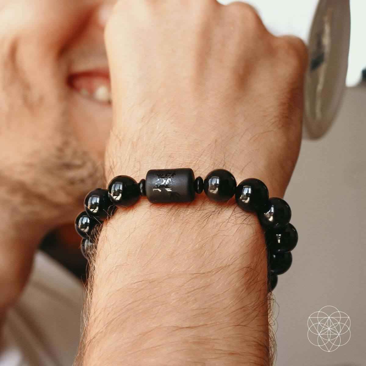 Black bead bracelet on wrist with cylindrical obsidian centerpiece